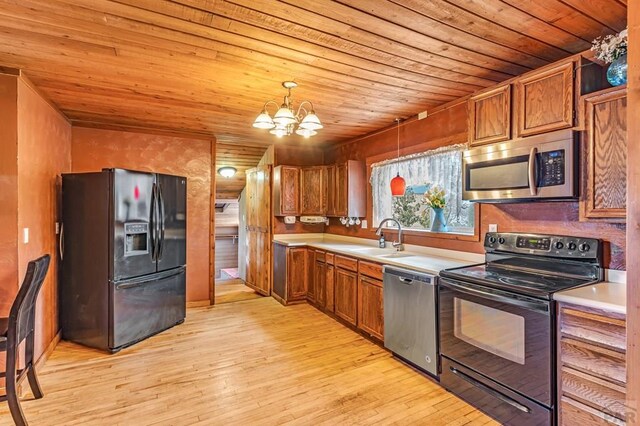 kitchen with brown cabinetry, pendant lighting, a sink, and black appliances