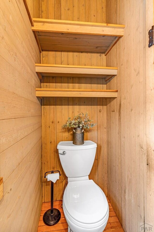 bathroom featuring wood walls and toilet