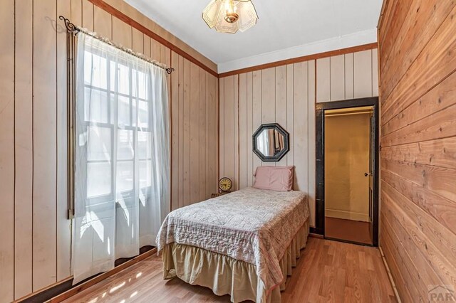 bedroom featuring light wood-style flooring and wooden walls