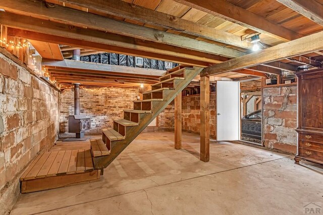 unfinished basement featuring stairway and a wood stove