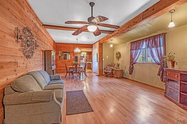 living area with ceiling fan, beam ceiling, wood walls, and wood finished floors