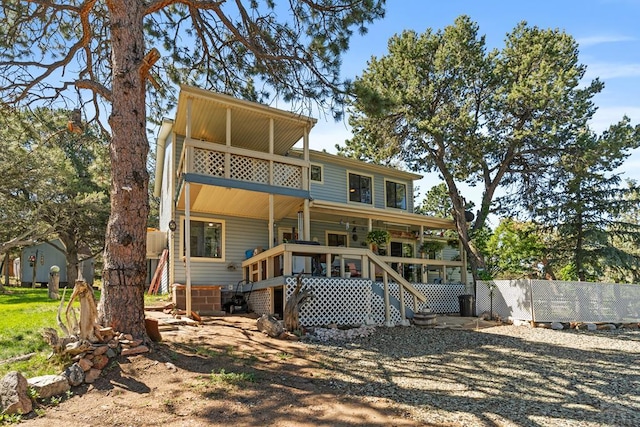 view of front of home featuring fence, a balcony, and stairs