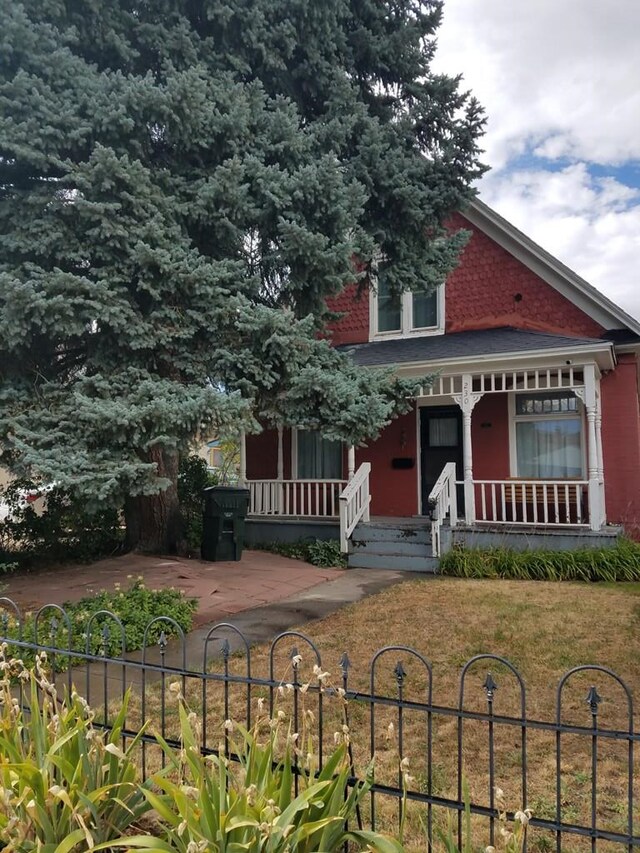 view of front facade with a fenced front yard, a front yard, and covered porch