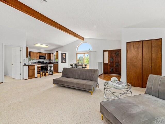 living room with lofted ceiling with beams and light colored carpet