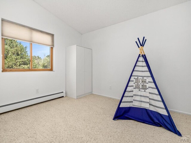 unfurnished bedroom featuring lofted ceiling, carpet, baseboards, and baseboard heating