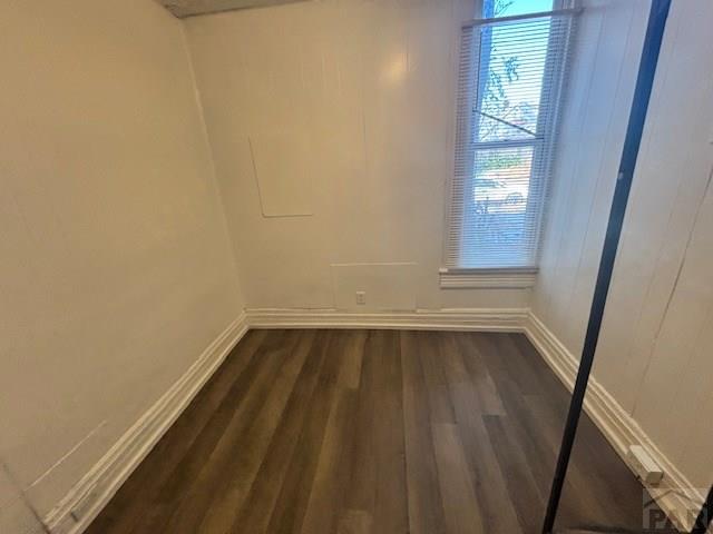 spare room featuring dark wood finished floors and baseboards