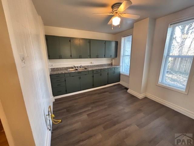 kitchen featuring dark countertops, dark wood-style flooring, a healthy amount of sunlight, and a sink