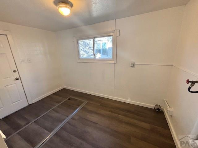 clothes washing area featuring dark wood-type flooring and baseboards