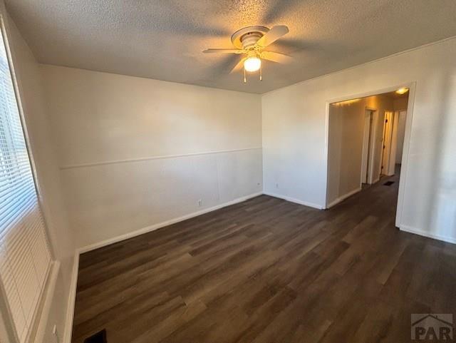 unfurnished room featuring a textured ceiling, ceiling fan, and dark wood-type flooring