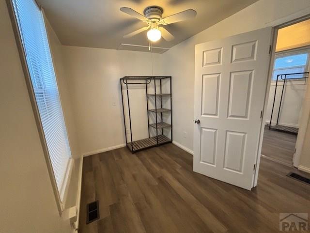 spare room with dark wood-style floors, baseboards, visible vents, and a ceiling fan