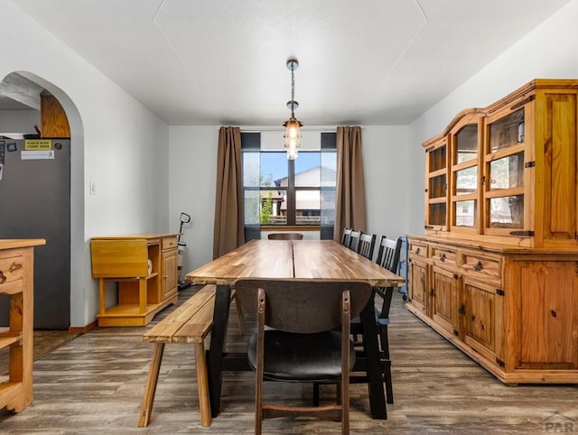 dining area with arched walkways and dark wood-type flooring