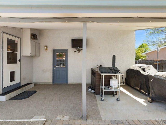 property entrance with a patio, fence, and stucco siding