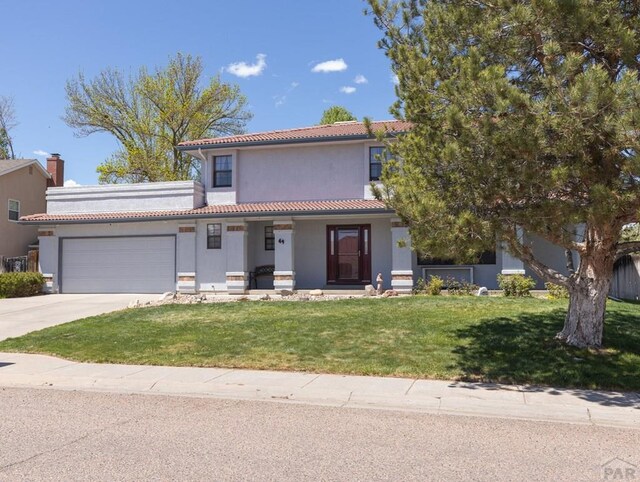 view of front of home with a tiled roof, an attached garage, a front lawn, a porch, and stucco siding