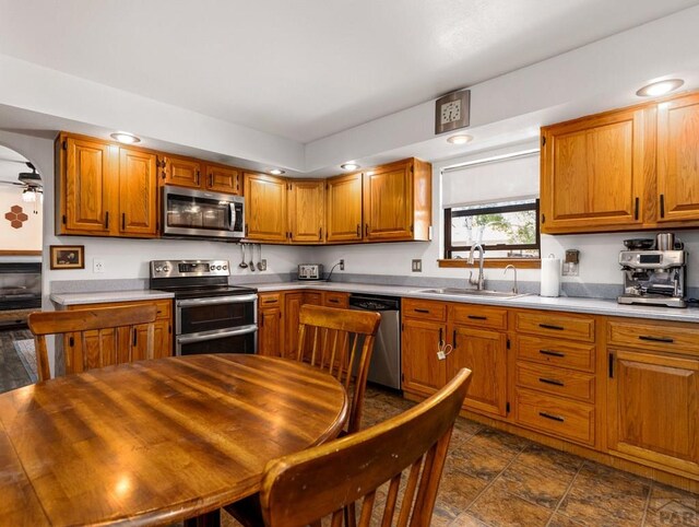 kitchen with appliances with stainless steel finishes, brown cabinets, light countertops, and a sink