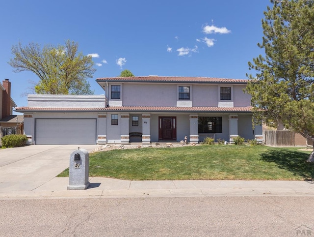 view of front facade with stucco siding, concrete driveway, fence, a garage, and a front lawn