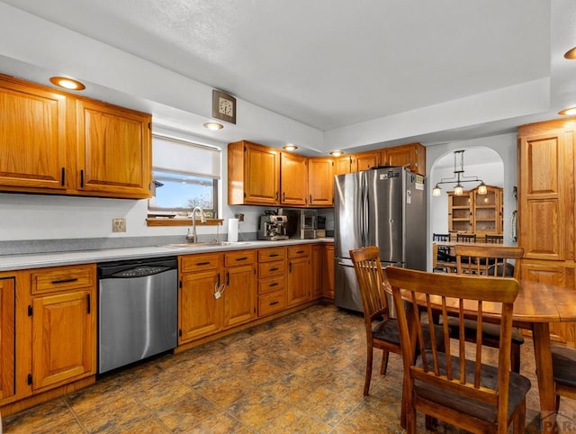 kitchen featuring a sink, brown cabinetry, stainless steel appliances, and light countertops