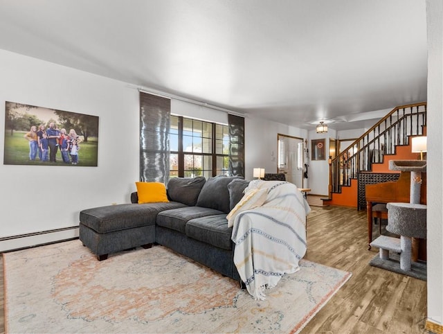 living area with a baseboard heating unit, stairway, and wood finished floors