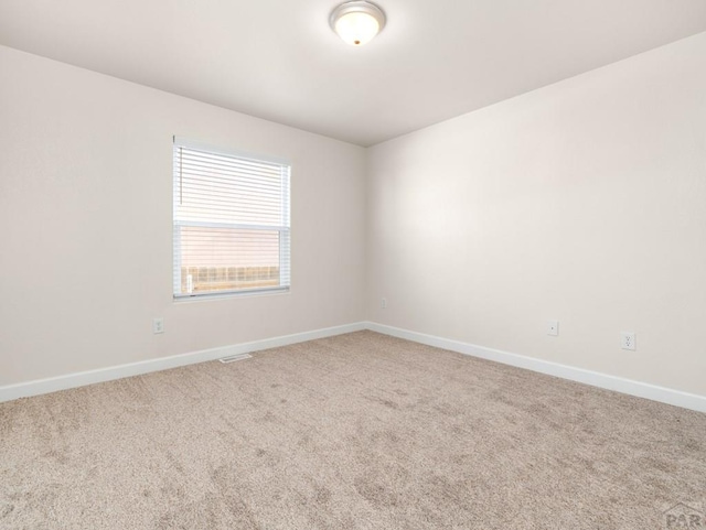 carpeted spare room with visible vents and baseboards