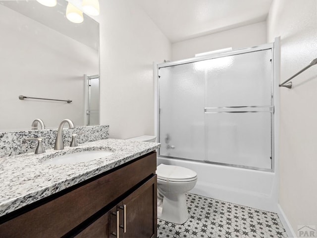 full bathroom with baseboards, vanity, toilet, and bath / shower combo with glass door