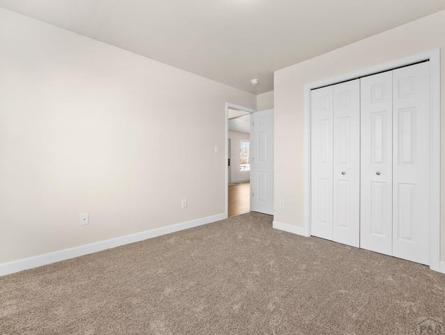 unfurnished bedroom with carpet floors, baseboards, and a closet