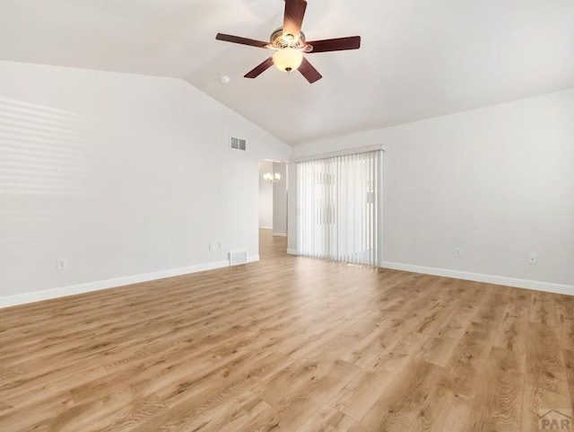 empty room featuring light wood finished floors, visible vents, vaulted ceiling, and ceiling fan with notable chandelier