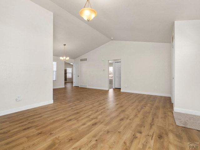 unfurnished living room featuring lofted ceiling, baseboards, an inviting chandelier, and wood finished floors