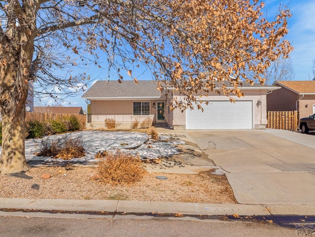 single story home with driveway, an attached garage, fence, and stucco siding