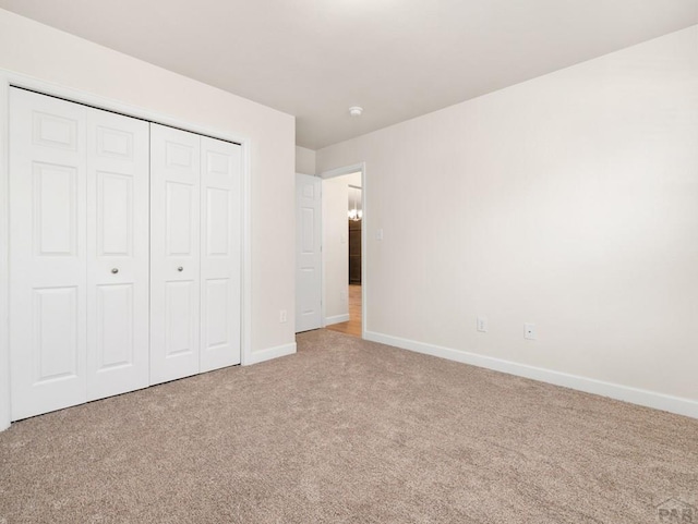 unfurnished bedroom featuring carpet floors, a closet, and baseboards