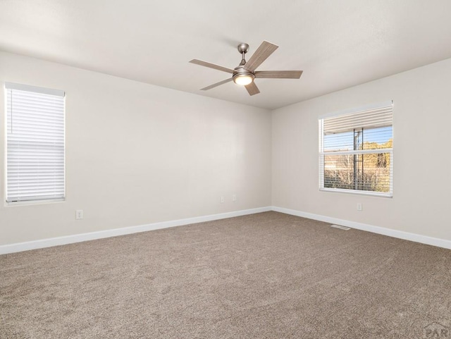 spare room featuring visible vents, carpet floors, a ceiling fan, and baseboards