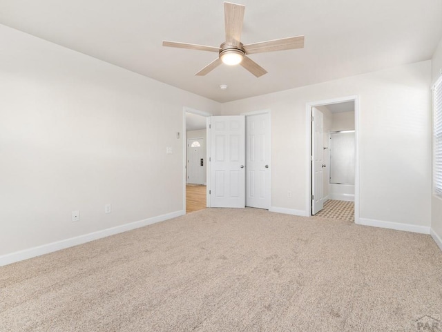 unfurnished bedroom with light carpet, ensuite bath, baseboards, and ceiling fan