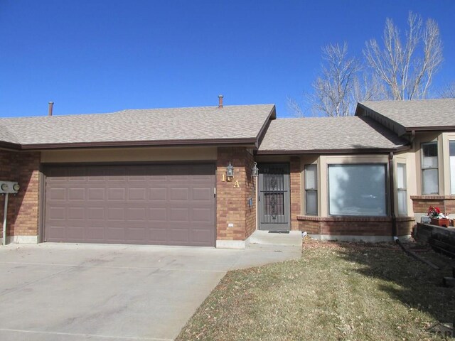 ranch-style home with a shingled roof, brick siding, and an attached garage