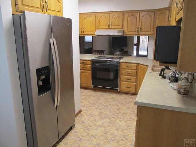 kitchen featuring black / electric stove, under cabinet range hood, a sink, light countertops, and stainless steel fridge