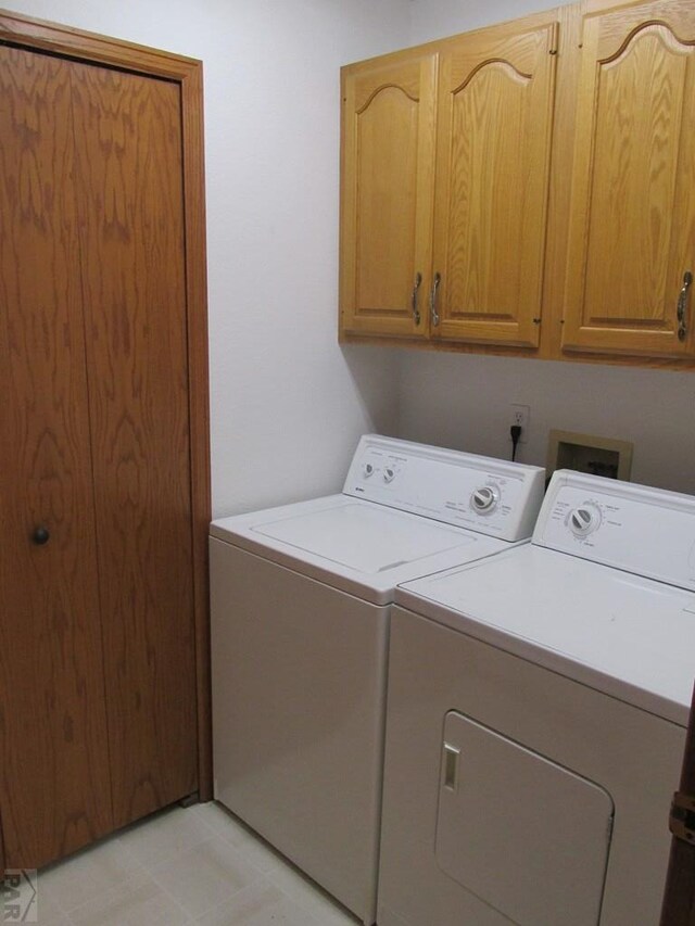 clothes washing area featuring washing machine and dryer and cabinet space