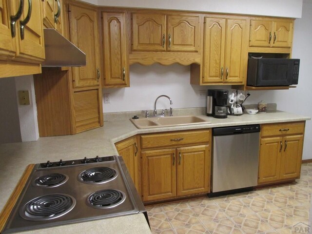 kitchen with brown cabinets, light countertops, a sink, black microwave, and dishwasher