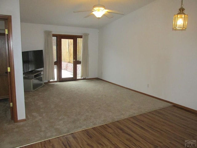 unfurnished living room with dark wood-type flooring, dark carpet, vaulted ceiling, and ceiling fan