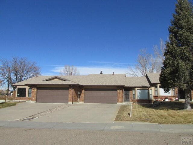 ranch-style house featuring a garage, concrete driveway, brick siding, and roof with shingles