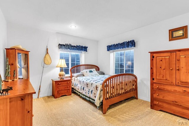 bedroom with light colored carpet and baseboards