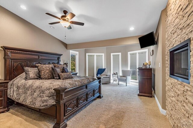 bedroom featuring light carpet, baseboards, a ceiling fan, vaulted ceiling, and a fireplace