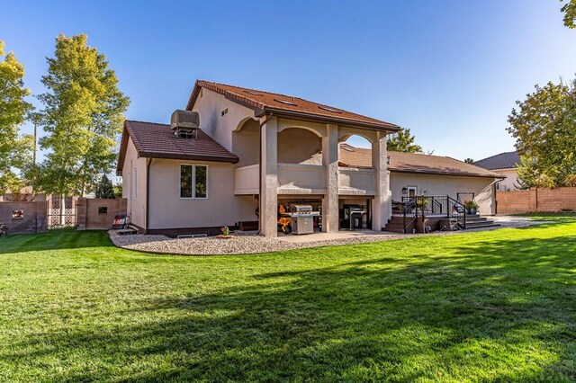 rear view of property with a yard, fence, central AC unit, and stucco siding