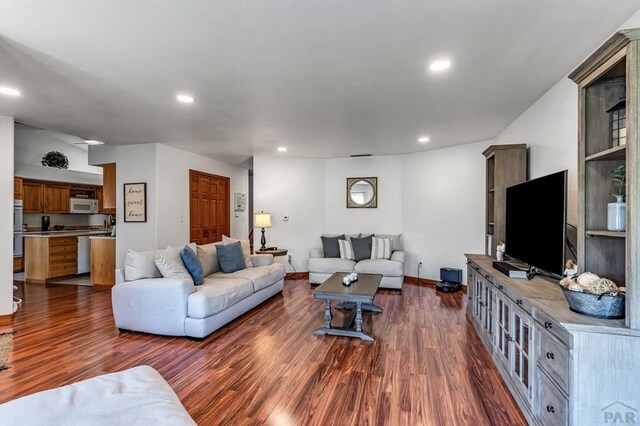 living room with recessed lighting, dark wood finished floors, and baseboards