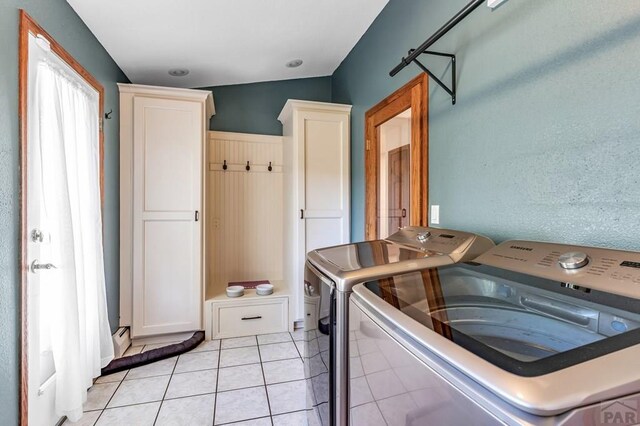 washroom featuring washing machine and dryer, cabinet space, and light tile patterned floors