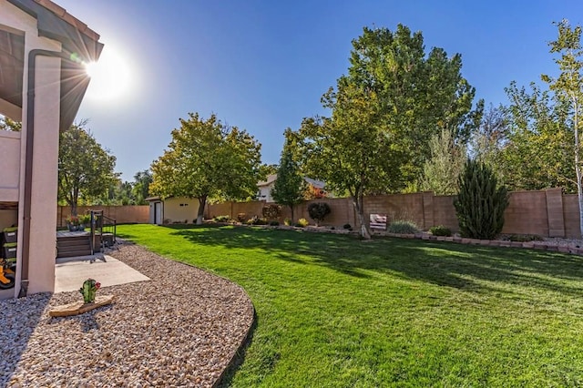 view of yard featuring a storage shed, a fenced backyard, an outdoor structure, and a patio