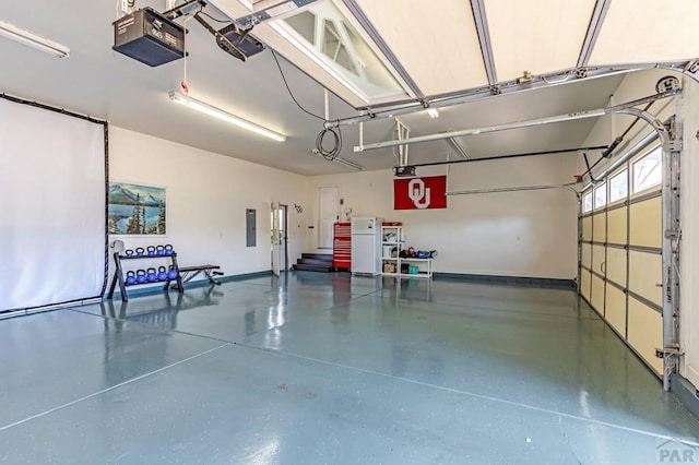 garage featuring a garage door opener, electric panel, and baseboards