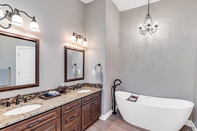 bathroom with a sink, backsplash, a freestanding bath, and double vanity