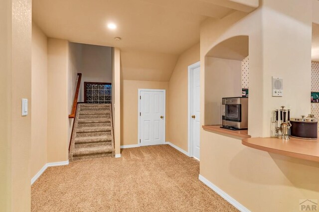 hall with light colored carpet, stairway, and baseboards