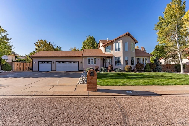 traditional-style home featuring a garage, fence, concrete driveway, stucco siding, and a front yard