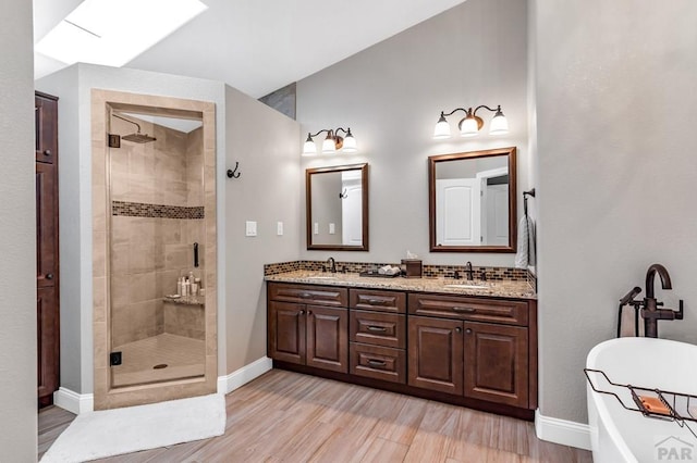 bathroom with double vanity, wood finished floors, a stall shower, and a sink