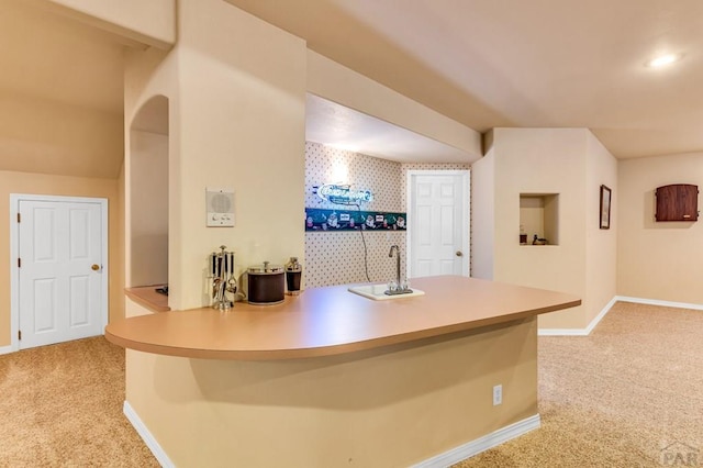 interior space featuring wallpapered walls, wet bar, baseboards, and light colored carpet