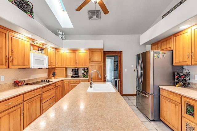 kitchen with white microwave, a sink, visible vents, light countertops, and stainless steel fridge