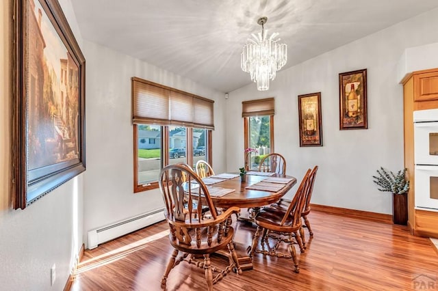 dining room with a baseboard heating unit, a notable chandelier, light wood-style flooring, and baseboards